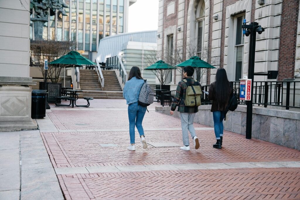 A group of students leisurely walking on a university campus pathway during the day.