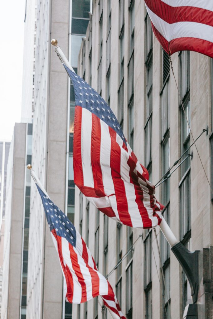 Row of American flags with stripe and star ornament on wall of embassy building in town