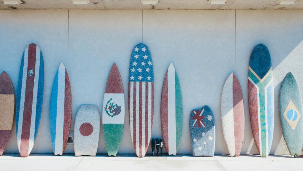 Vibrant surfboards with flag designs lined up against a concrete wall.